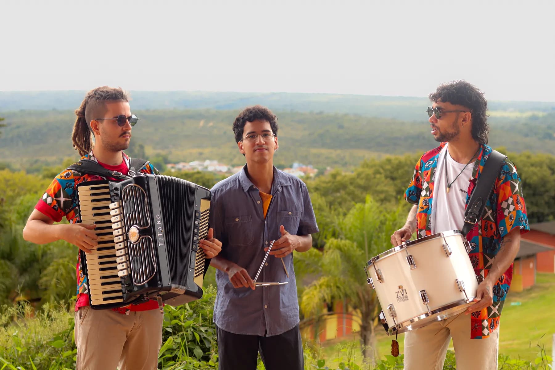 O Trio Massapé com seus instrumentos, tendo o cerrado ao fundo